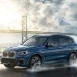blue BMW X3 driving in front of golden gate bridge in rain