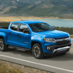 This is a blue Chevy Colorado driving near a lake.