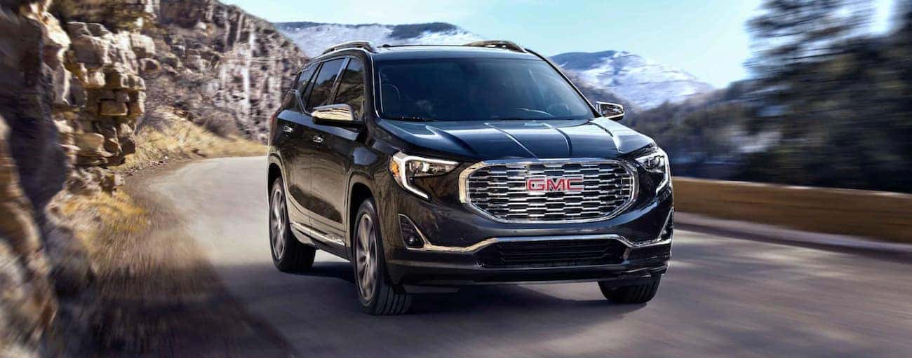 A black 2021 GMC Terrain is driving on a mountain road.