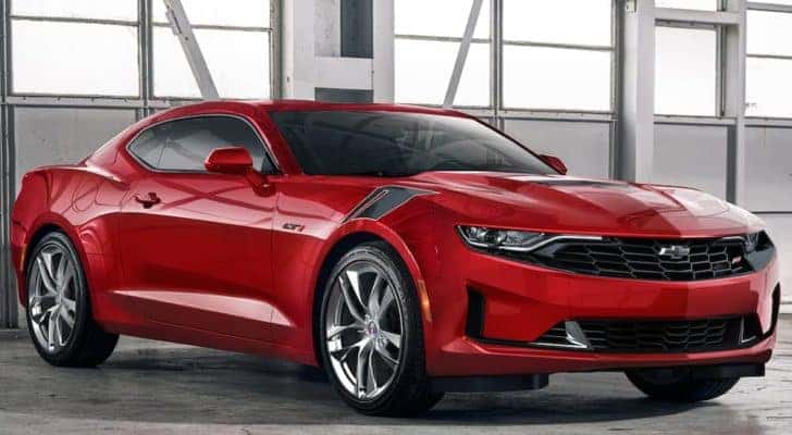 A red 2021 Chevy Camaro is parked in a bright warehouse.