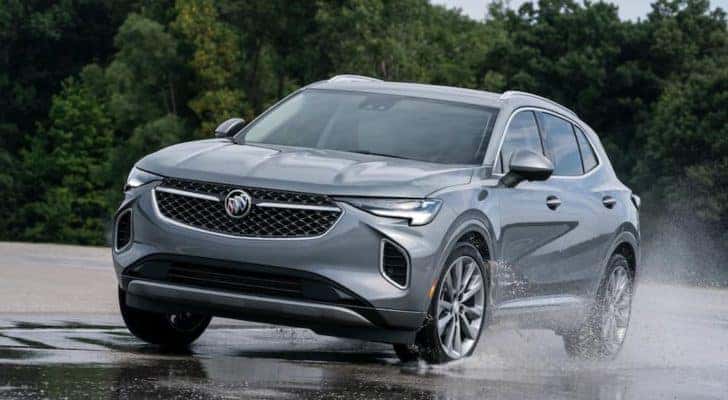 A grey 2021 Buick Envision, from a Louisville Buick dealer, is driving through puddles on pavement.