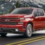A red 2021 Chevy Silverado is shown driving down the highway after leaving a Louisville Chevy dealer.