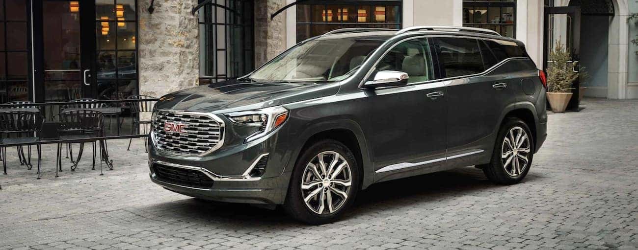 A grey 2021 GMC Terrain Denali is parked on a cobblestone street.