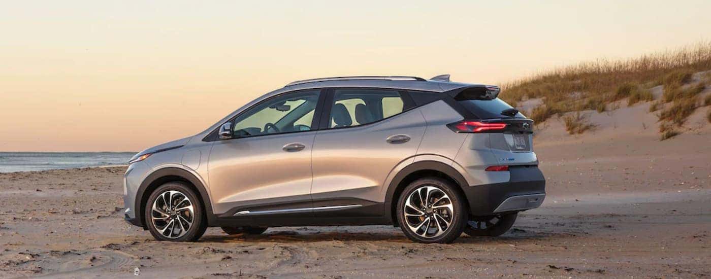 A silver 2022 Chevy Bolt EUV a Chevy EV is shown from the side parked on a beach.