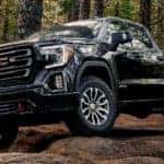 A black 2019 GMC Sierra AT4 is off-roading in the woods.