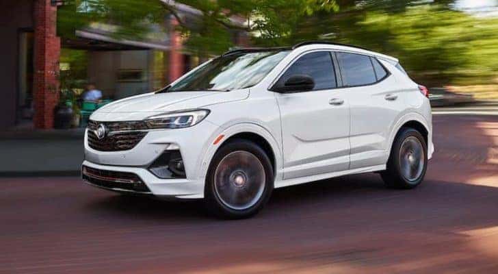A white 2021 Buick Encore GX is driving downtown on a brick road.