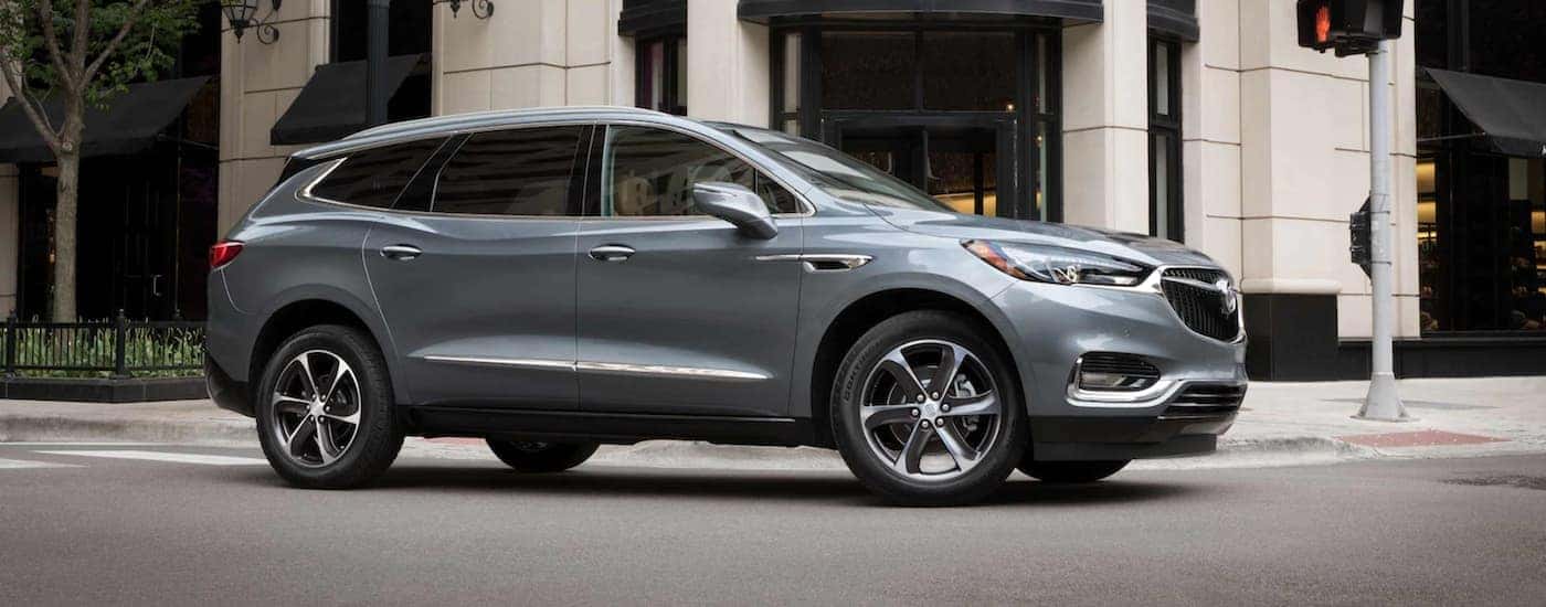 A grey 2021 Buick Enclave is driving on a city street after leaving an Indiana Buick dealership.