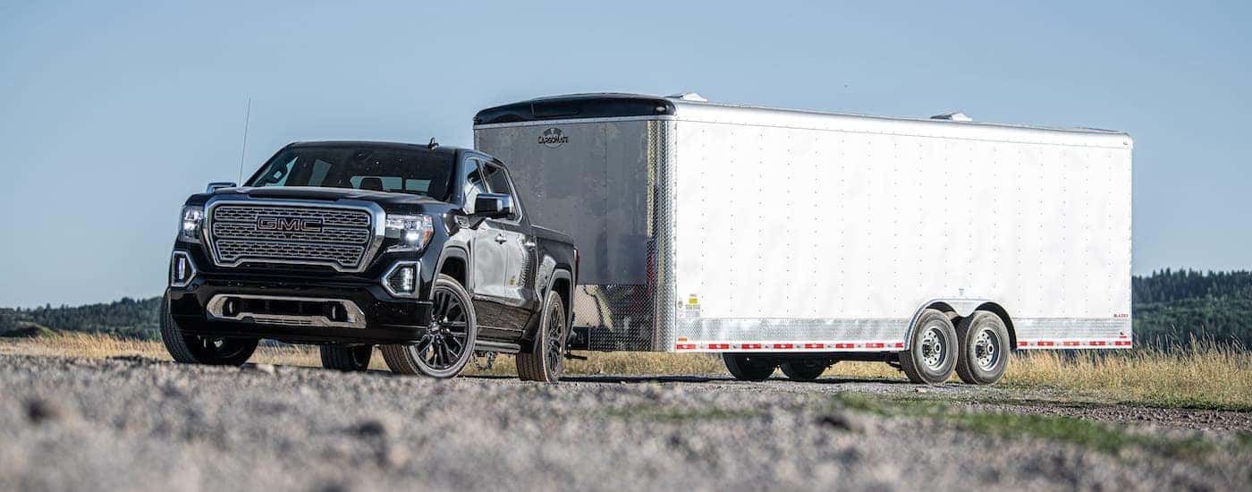A black 2021 GMC Sierra 1500 Denali is towing a large white enclosed trailer.