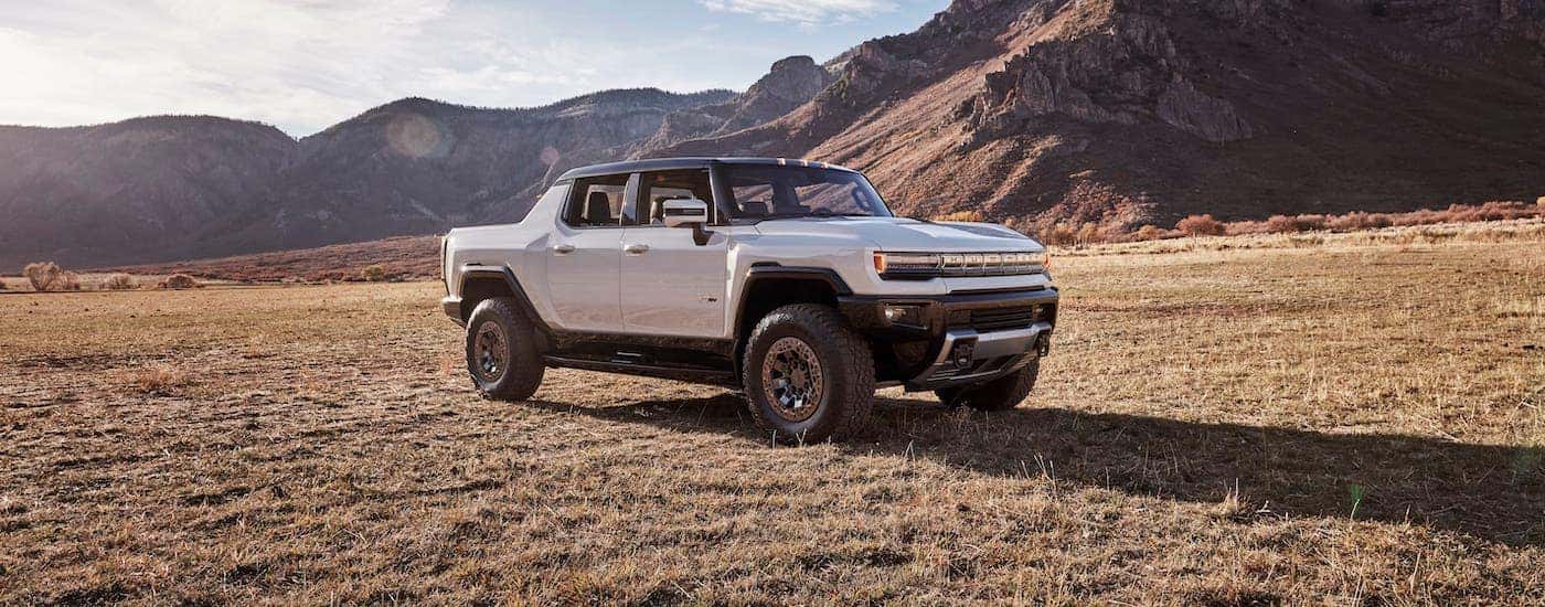 A white 2022 GMC Hummer EV is parked in front of mountains.