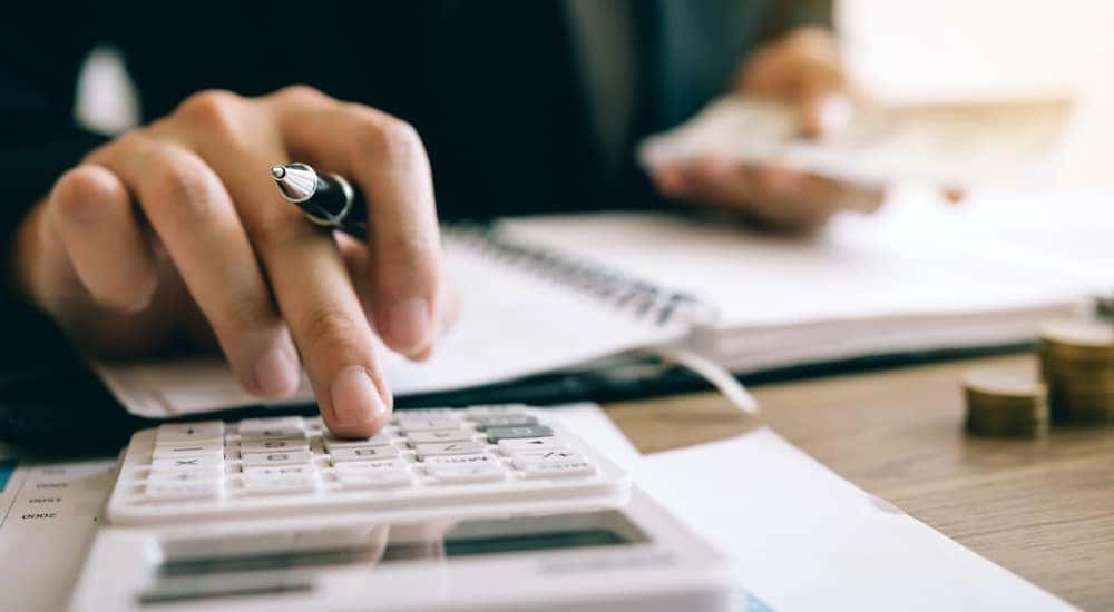 A man is holding a pen as he uses a calculator to budget.