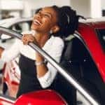A woman is stepping out of a car at a Louisville used car dealer.