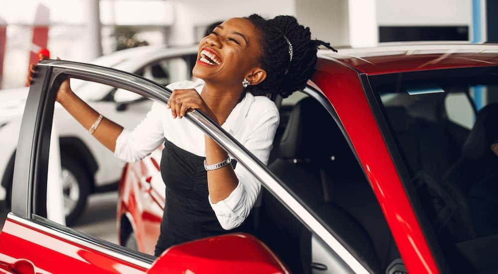 A woman is stepping out of a car at a Louisville used car dealer.