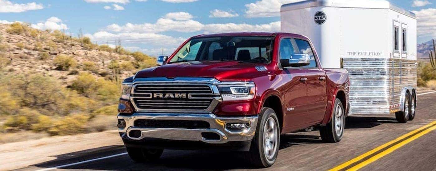A red 2019 ram 1500 is shown from the front towing a closed trailer.