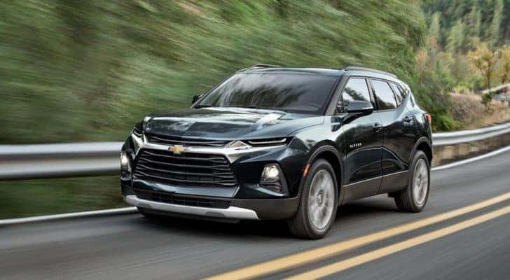 A black 2020 Chevy Blazer is driving down a two lane road after leaving a used Chevy Dealership near you.