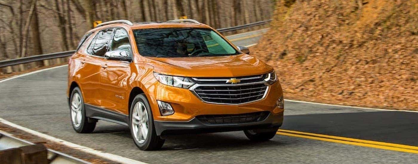 An orange 2018 Chevy Equinox is shown from the front driving on an open road after leaving a used car dealer in Louisville.