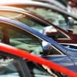 A close up shows used cars for sale parked at an angle.