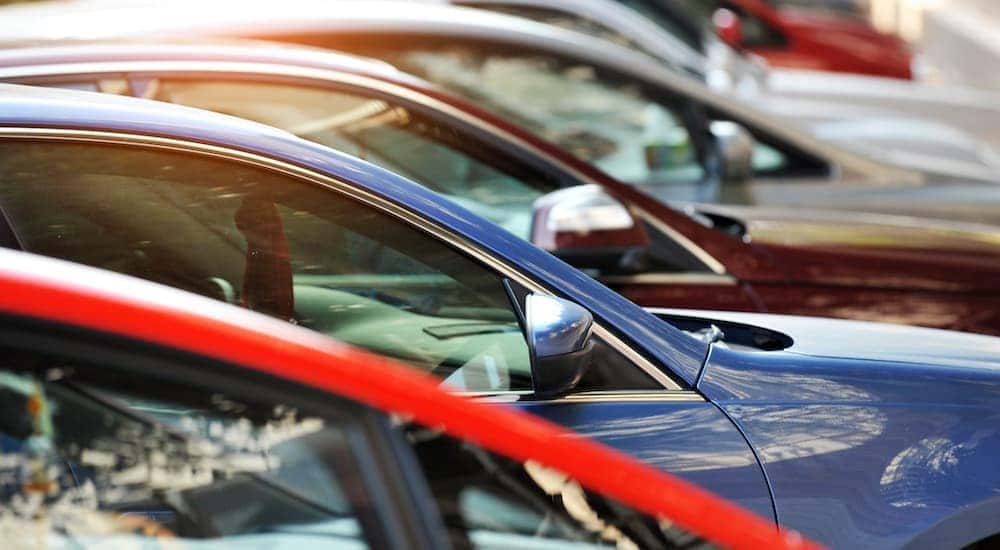A close up shows used cars for sale parked at an angle.