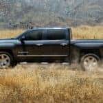 A black 2018 Chevy Silverado 1500 is shown driving through a hay field after leaving a used truck dealership.