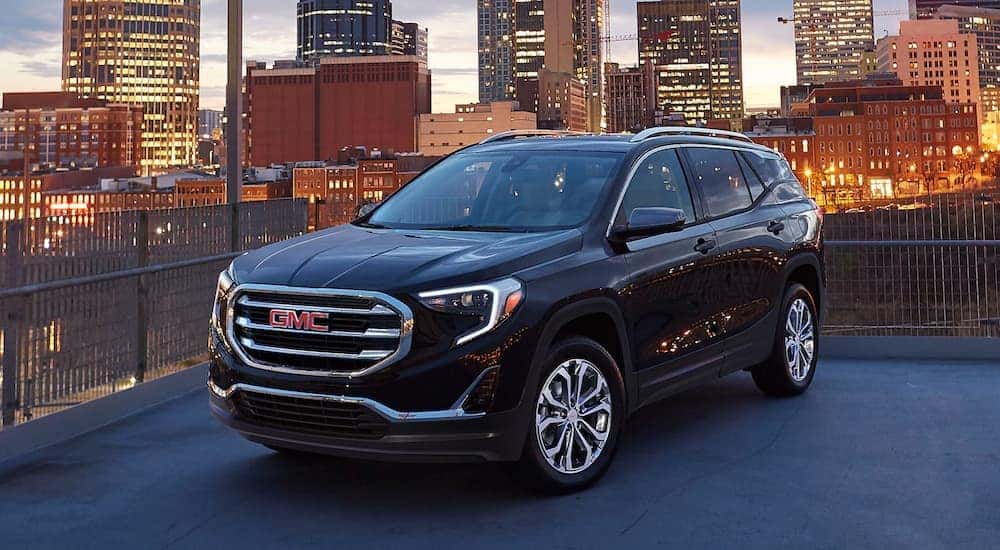A black 2020 GMC Terrain SLE is shown parked with a city in the background after leaving a Louisville used car lot.