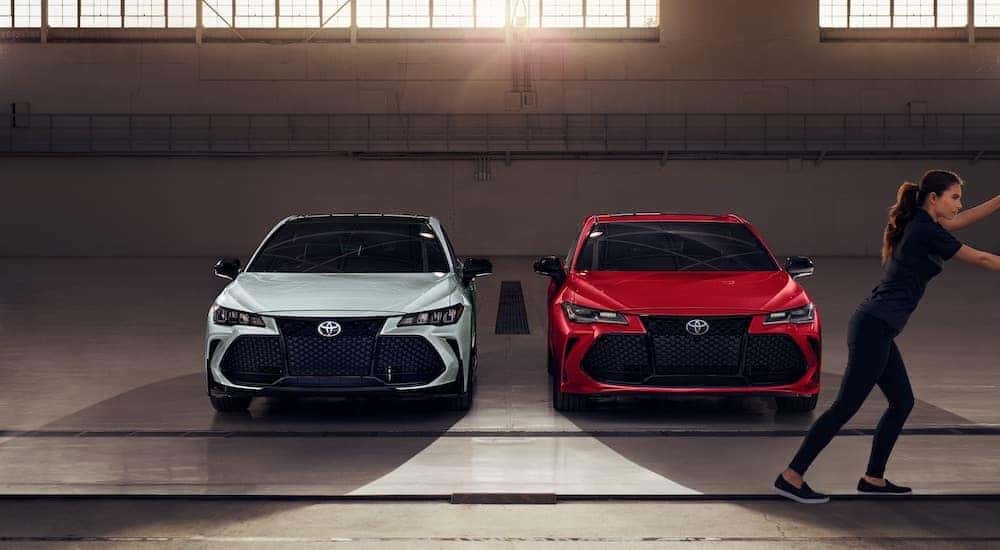 A white and a red 2020 Toyota Avalon are shown parked in a warehouse.