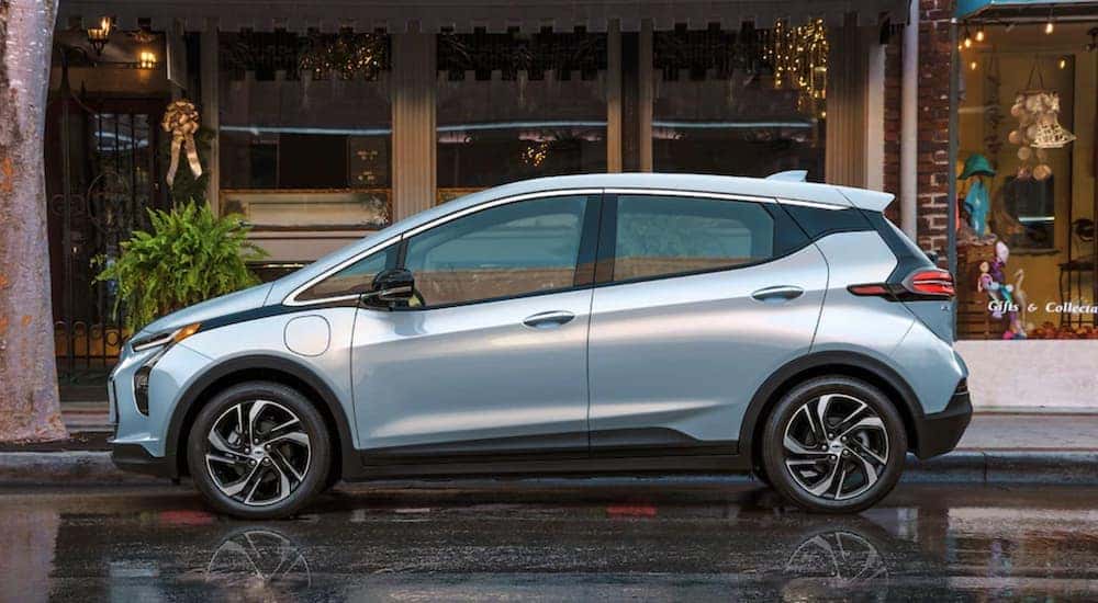 A light blue 2022 Chevy Bolt EV is shown from the side parked in front of a store.