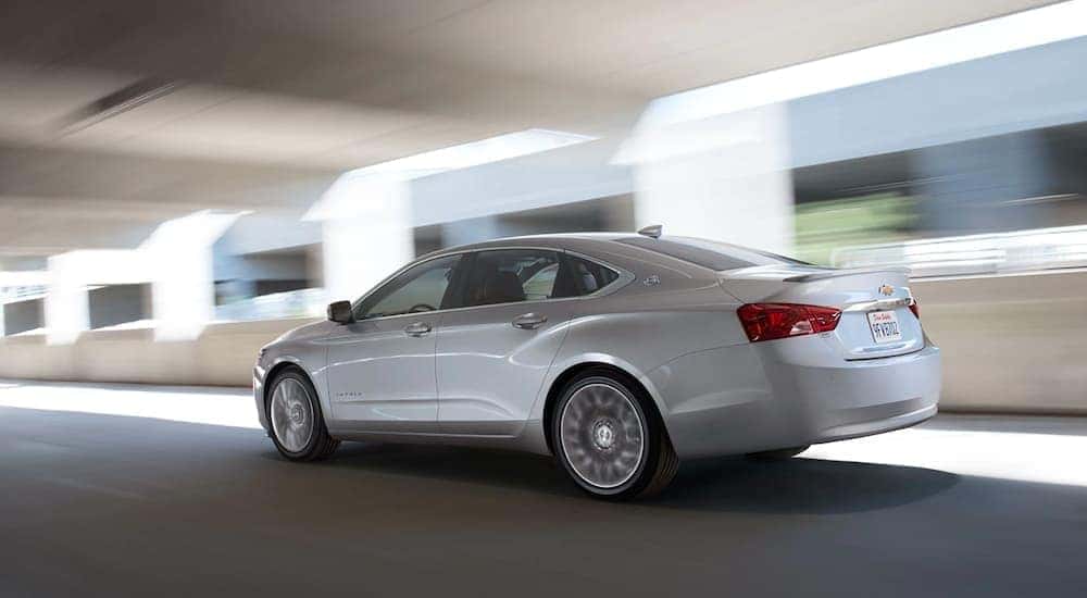 A white 2020 Chevy Impala is shown from the side driving after leaving a used Chevy dealer.