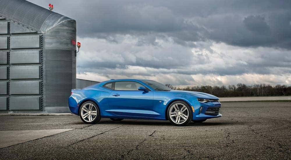 A blue 2010 Chevy Camaro RS is shown from the side parked in front of a hanger after visiting a Louisville used Chevy dealer.