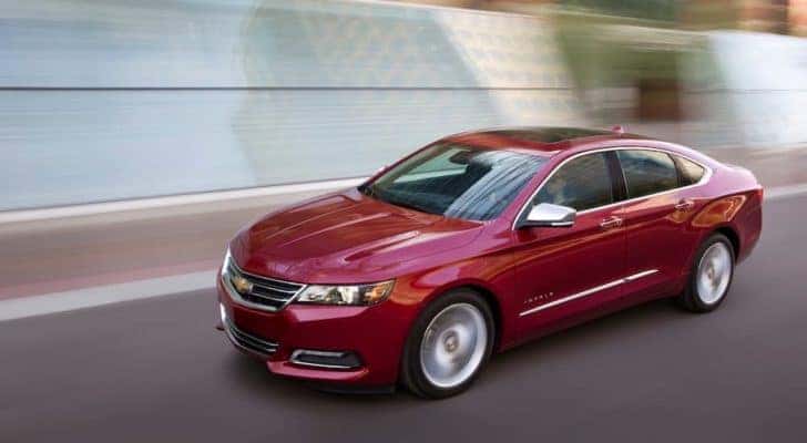 A red 2018 Chevy Impala LTZ is shown driving past a blurred background after visiting a Louisville used Chevy dealer.