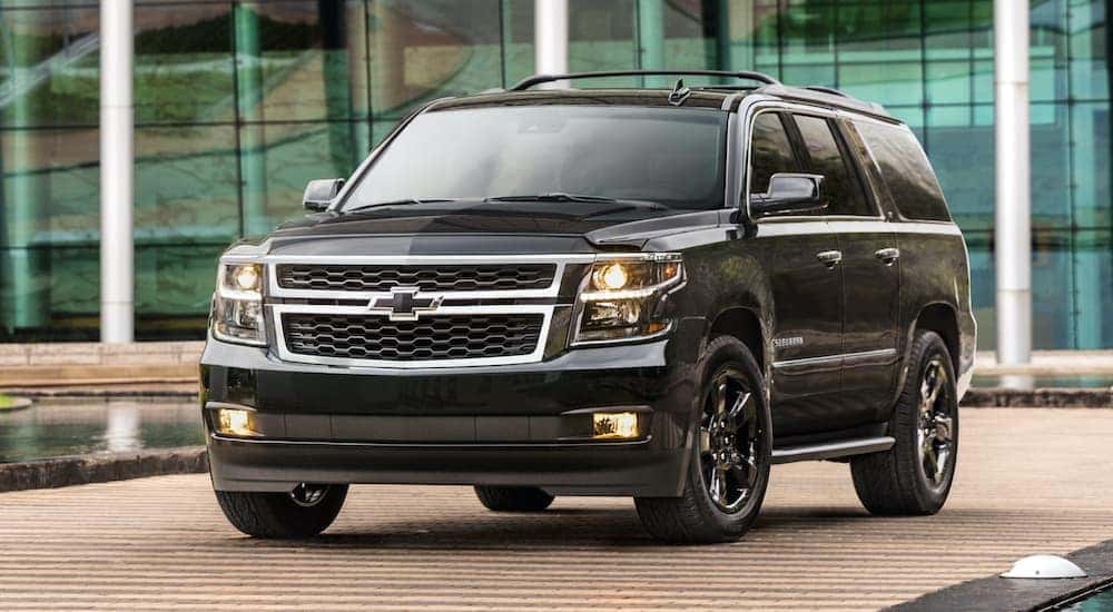 A black 2018 Chevy Suburban is shown parked in front of a modern building.