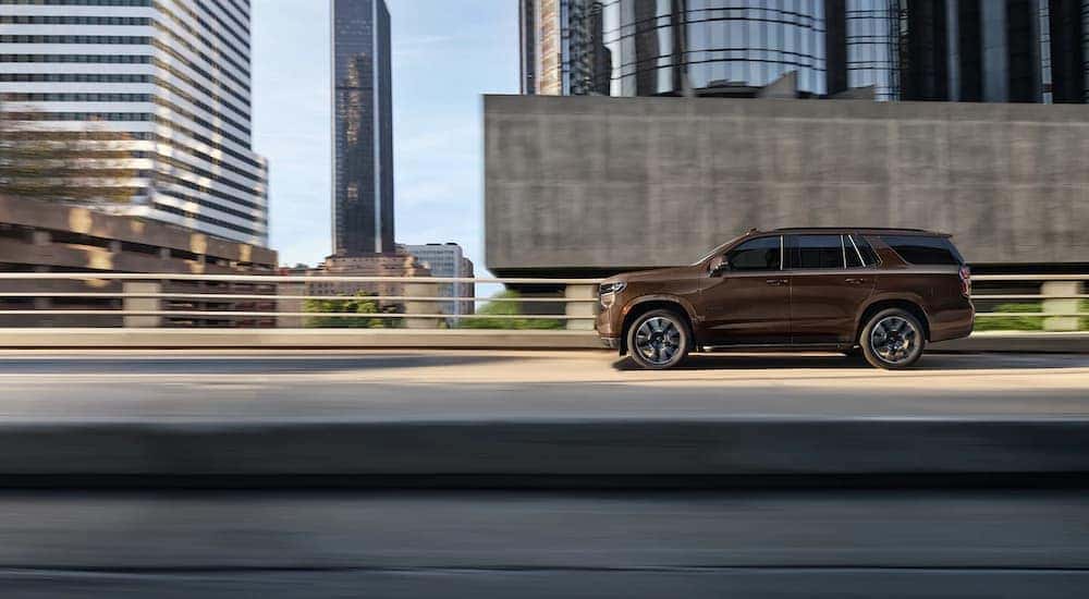 A brown 2022 Chevy Tahoe is shown from the side leaving a Louisville Chevy dealer.