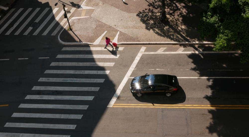 A black vehicle is shown stopped at a crosswalk on their way to a used car dealer in Louisville.
