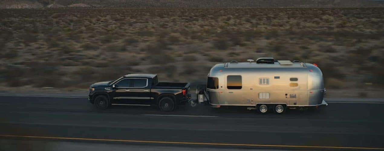A black 2022 GMC Sierra 1500 is shown towing an airstream trailer on an open road after winning a 2022 GMC Sierra 1500 vs 2022 Toyota Tundra comparison.
