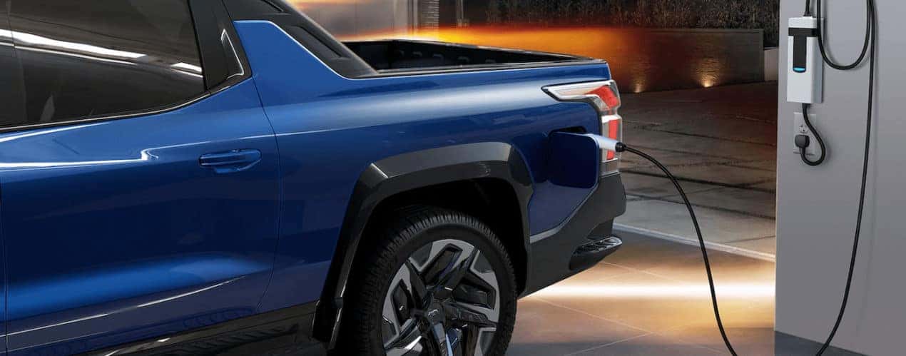 A blue 2024 Chevy Silverado EV is shown at an EV charging station.