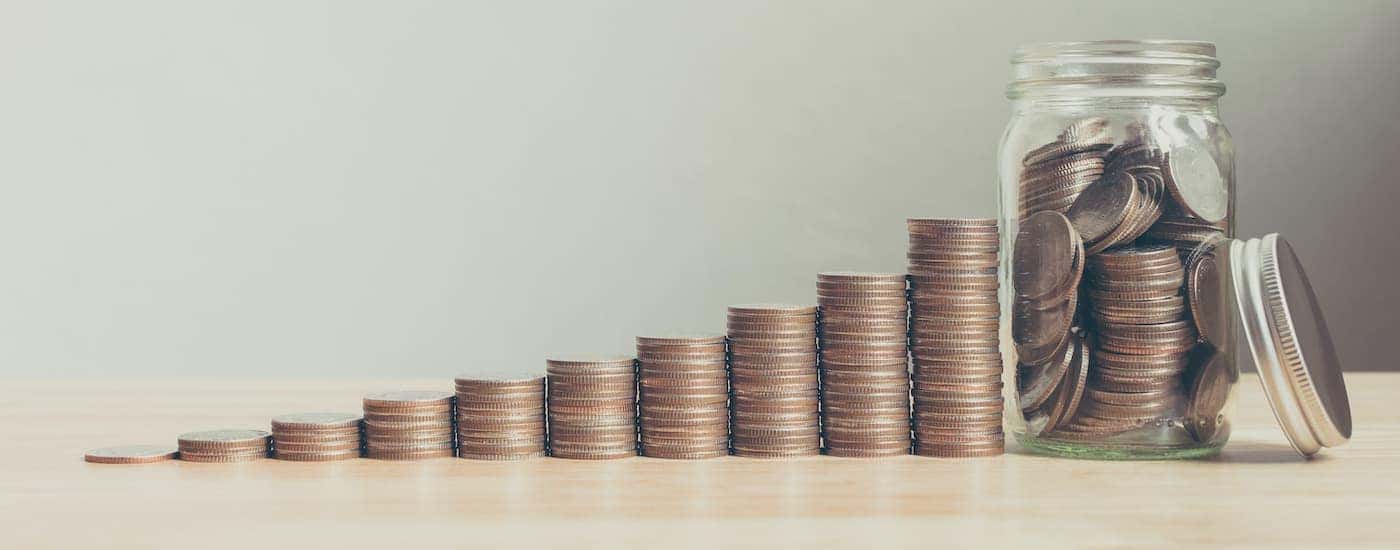 A stack of graduating coins is shown leading to a jar full of coins.