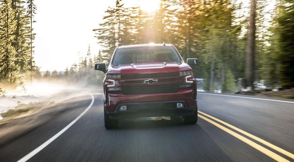 A red 2020 Chevy Silverado 1500 is shown driving on a sunny day after visiting a used Chevy Dealership near you.