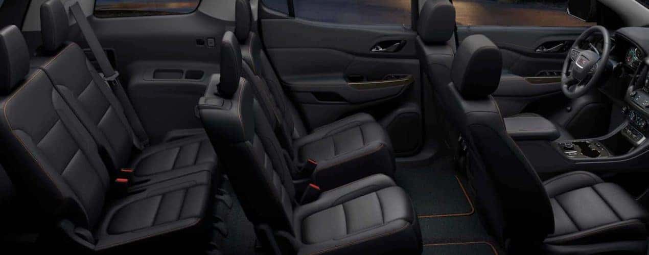 The black interior of a 2022 GMC Acadia shows three rows of seating.