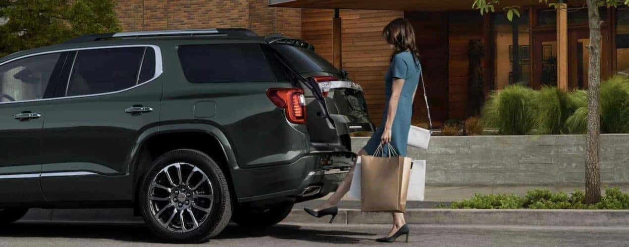 A green 2022 GMC Acadia is shown from the side as a person uses the lift gate.