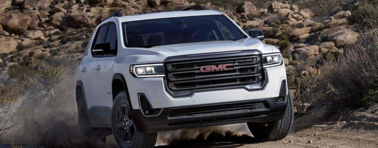 A white 2022 GMC Acadia AT4 is shown from the front off-roading after winning a 2022 GMC Acadia vs 2022 Honda Pilot comparison.