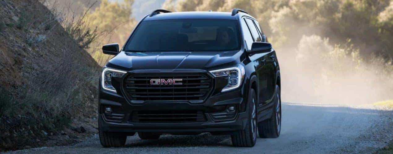 A black 2022 GMC Terrain is shown from the front driving on a dirt road.