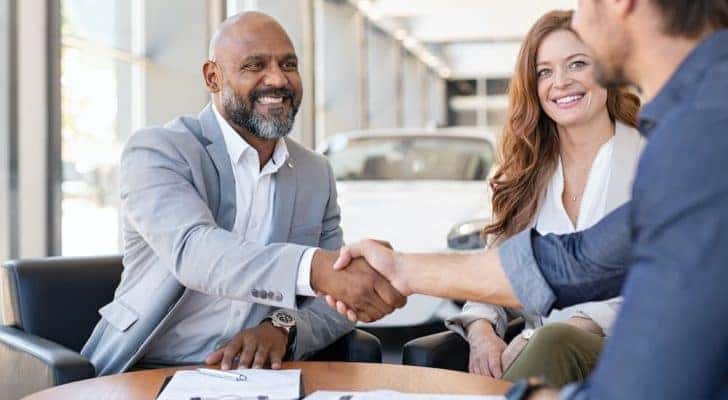 Two people are talking to a salesperson at a Chevy dealer in Louisville.