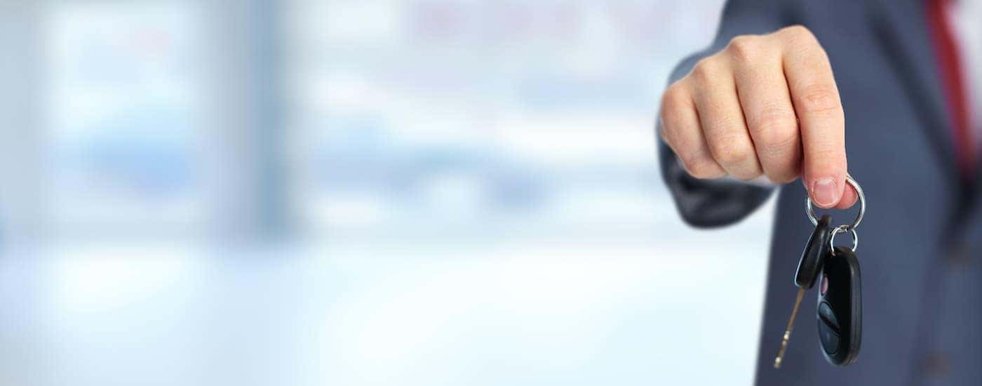 A salesperson is shown holding a key at a Louisville used car dealer.