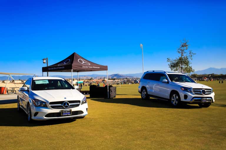 two white Mercedes-Benz vehicles parked on the grass in front of a pop-up tent