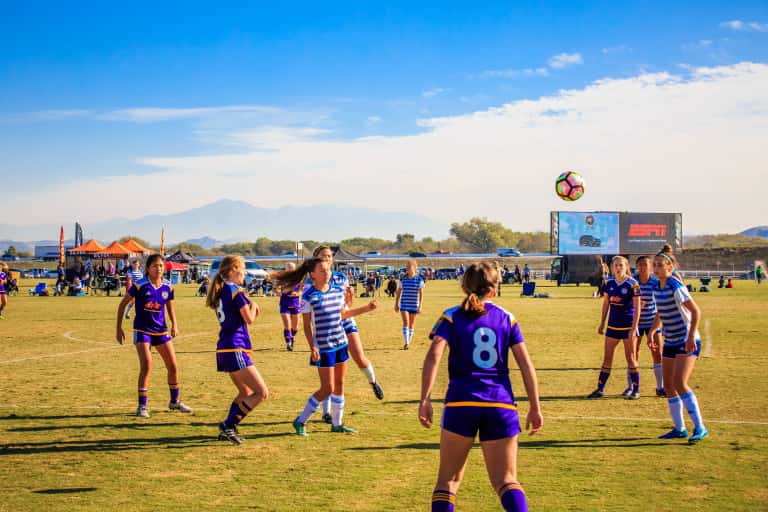 a group of girls watching the soccer ball in the air