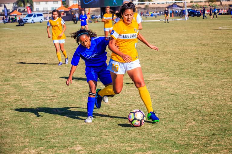 two girls fighting for possession over the soccer ball