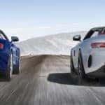 Two Mercedes-Benz convertibles driving side-by-side on highway