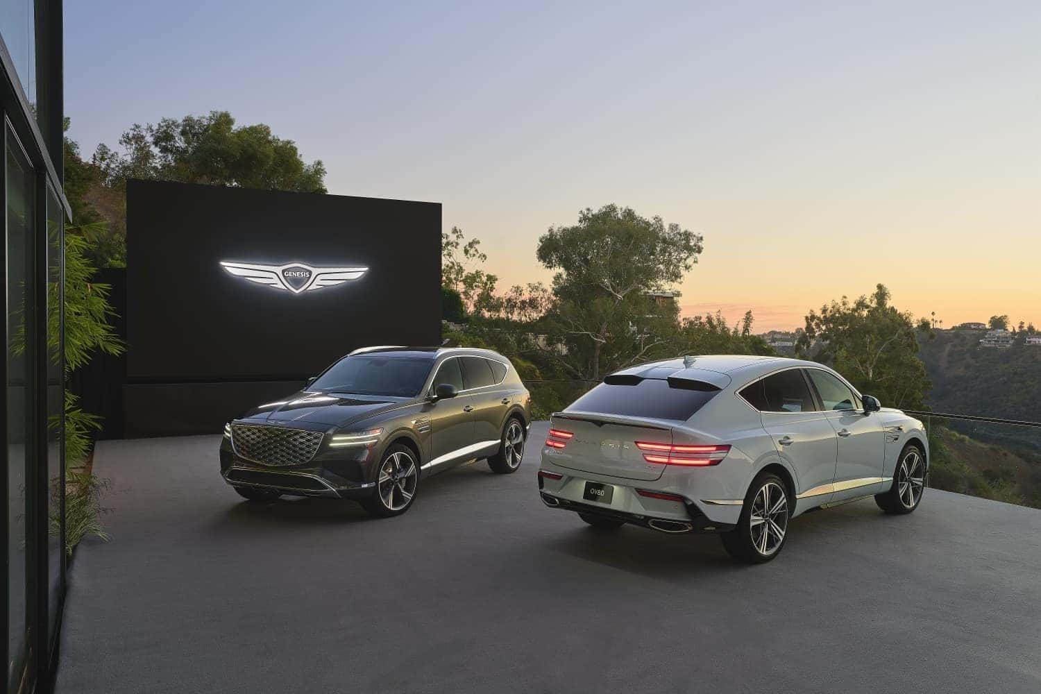2 Genesis GV80 parked with logo on building in the background.