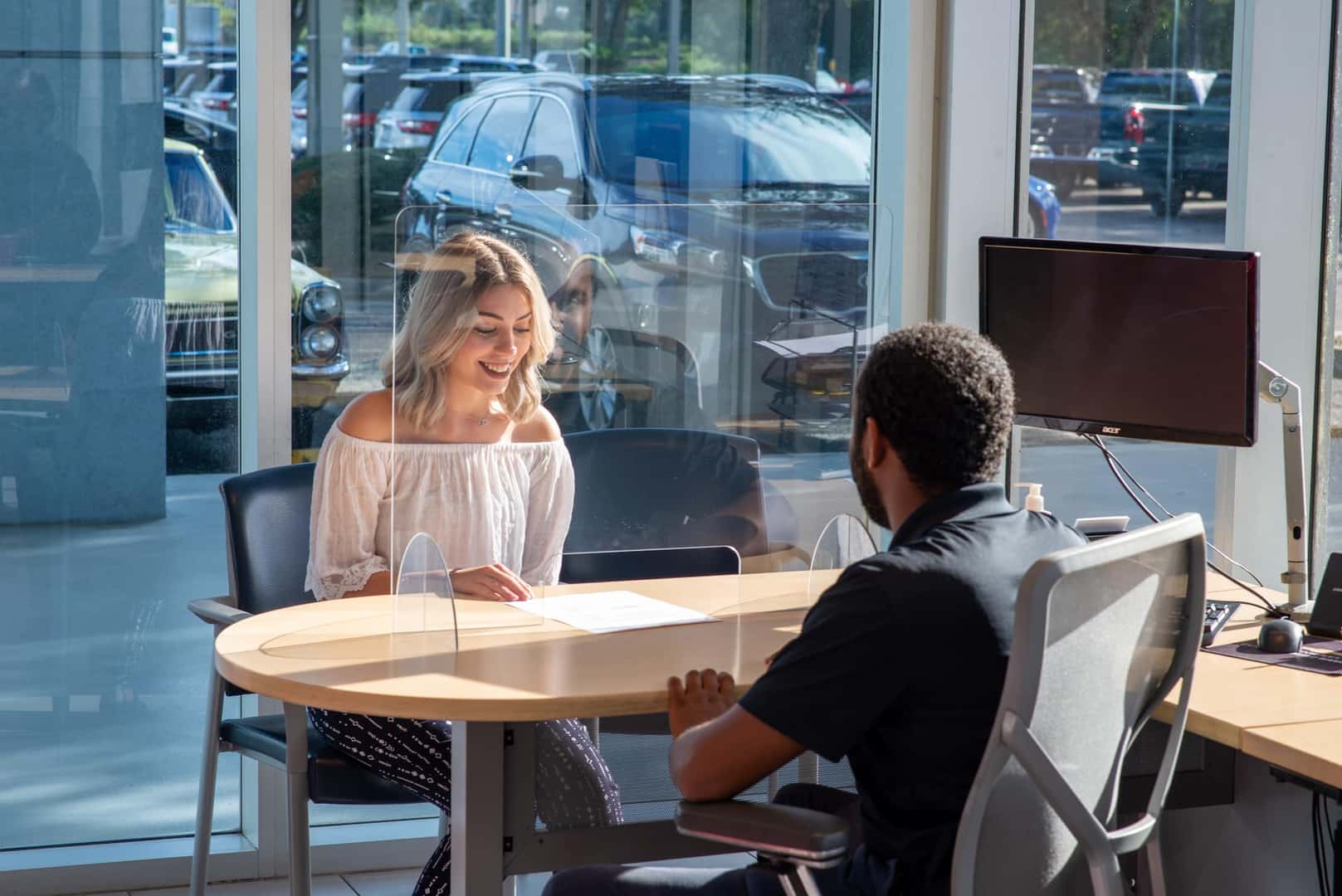 A girl sitting inside a dealership, looking at her computer.