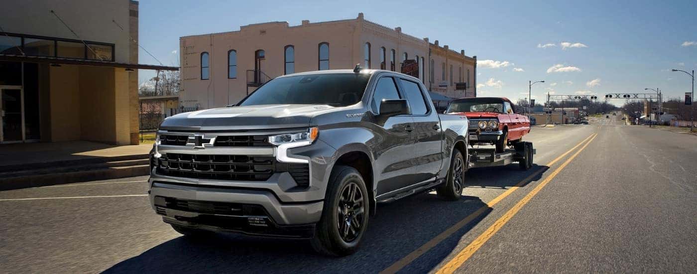 A grey 2024 Chevy Silverado 1500 towing a trailer in a city