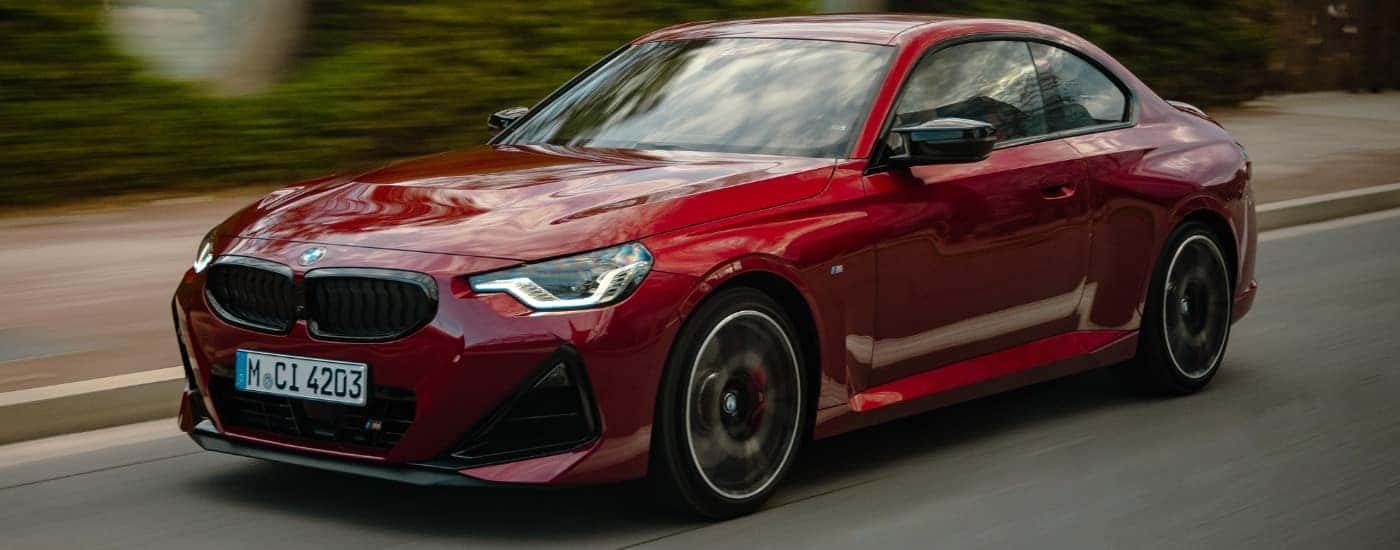 A red 2022 BMW M240i driving on a highway