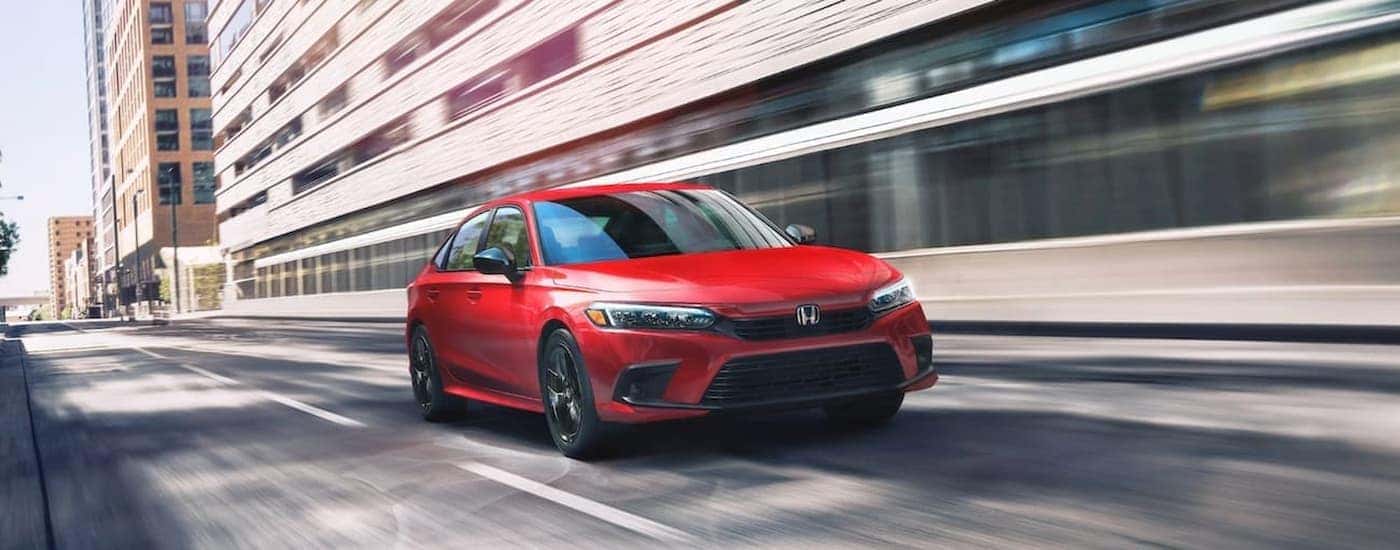 A red 2022 Honda Civic driving down a sunny city street